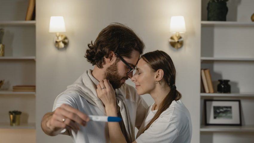 Happy couple awaiting new beginnings with a positive pregnancy test in warm home setting.
